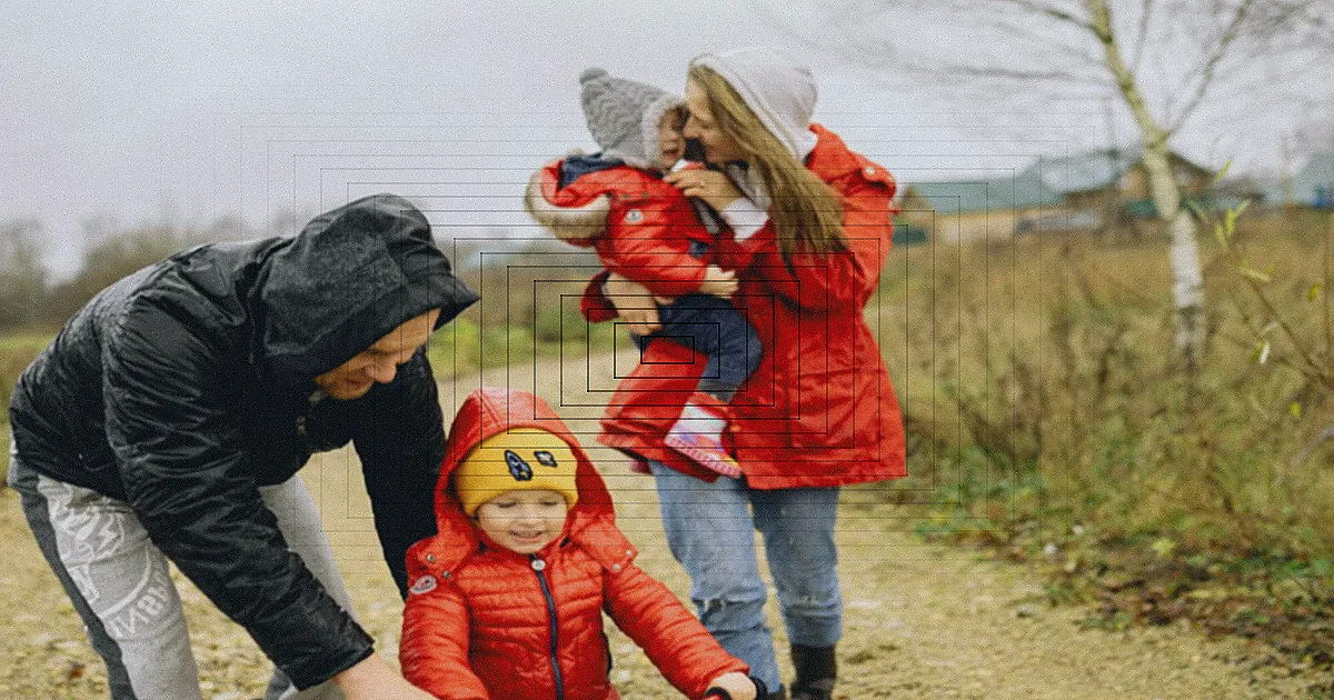 A family biking through a city intersection on a cloudy day, wearing helmets for safety. — Foto: Saplak / Pexels